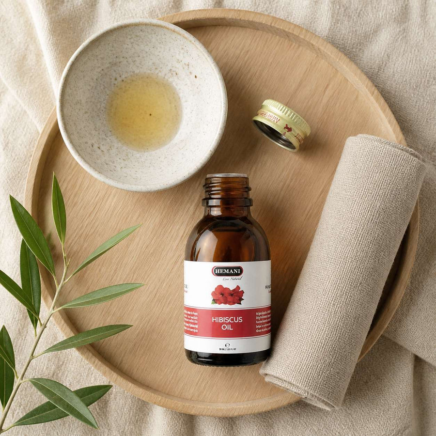 4 Huiles d'Hibiscus 30mL 100% Naturelle Hemani – rituel d'utilisation vu du dessus, ambiance naturelle zen