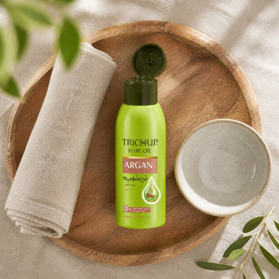 Huile capillaire à l'Argan Trichup - 100mL – rituel d'utilisation vu du dessus, ambiance naturelle zen